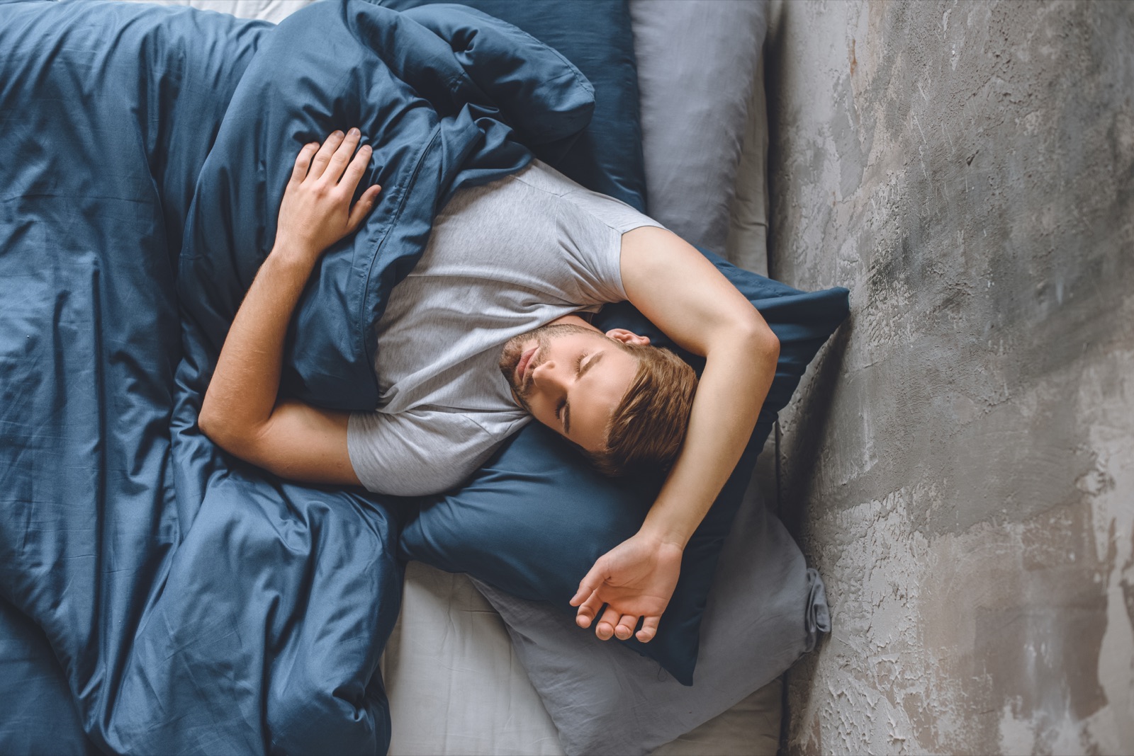 Elevated view of a man sleeping peacefully, wrapped in soft bedding